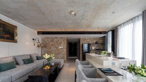 Una sala de estar moderna con un sofá, una mesa de centro y un comedor con sillas y una mesa dispuesta para dos personas.