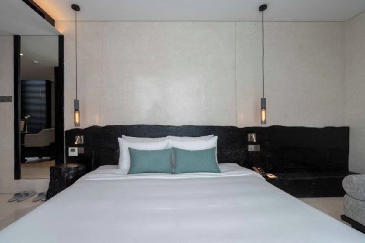A modern bedroom with a large bed, two bedside tables, and a headboard.