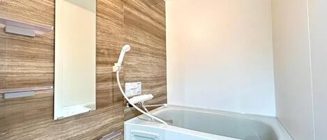 Un baño moderno con pared de madera, una bañera blanca y un espejo.