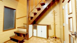 Eine Holztreppe mit Geländer, eine Sitzbank und ein Kleiderständer.