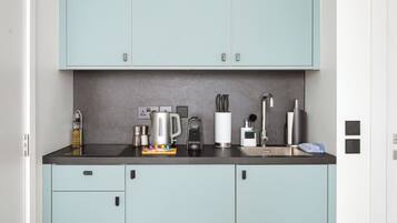 Une cuisine moderne avec des meubles de couleur bleu clair, un plan de travail noir et divers appareils électroménagers.