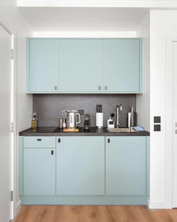 Una cocina moderna con armarios azul claro, encimera negra y varios electrodomésticos.