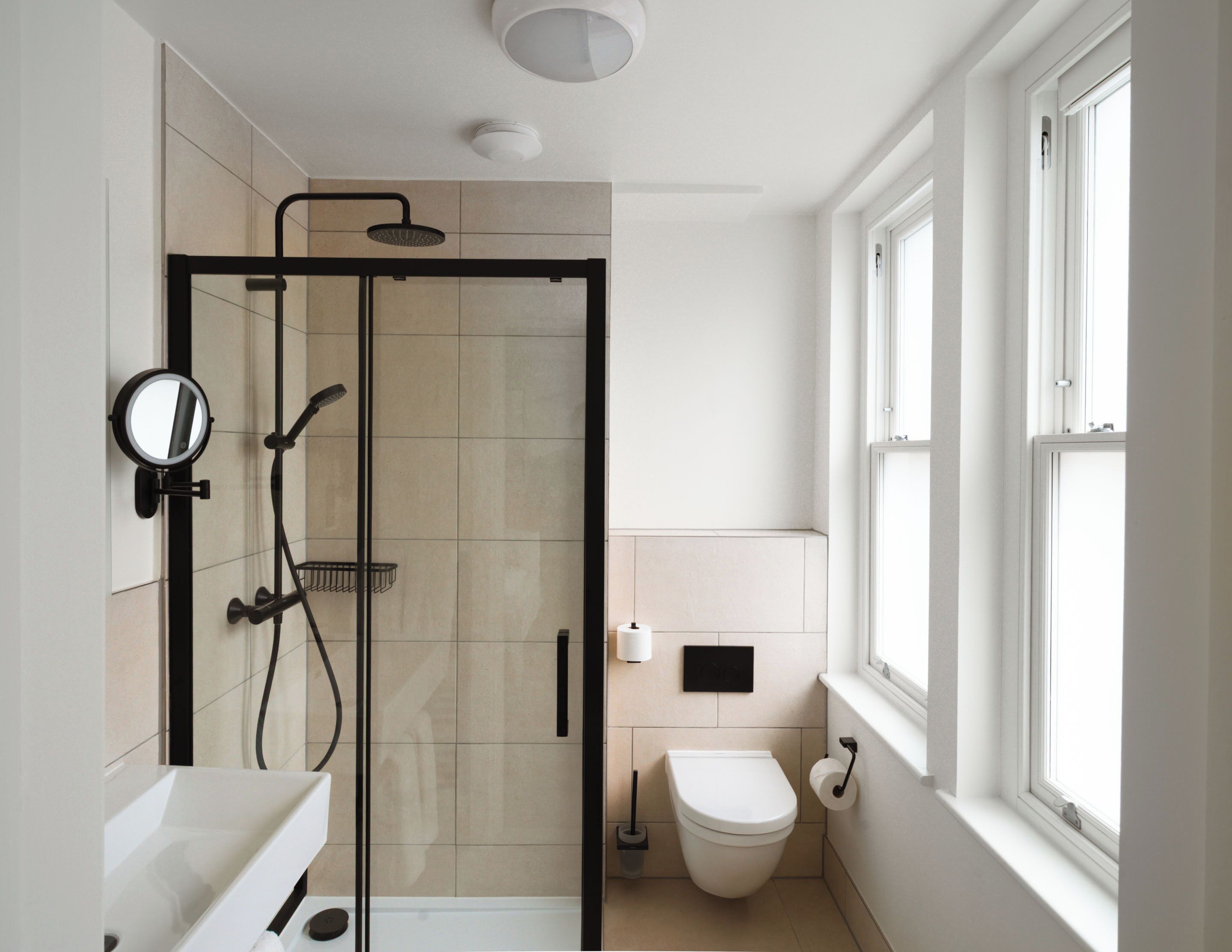 Un baño moderno con cabina de ducha de vidrio, inodoro y lavabo.