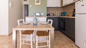 A modern kitchen with white cabinets, a wooden countertop, a built-in oven, and a refrigerator. - Charming South Garden Apartment, Pets Allowed, Parking, Barfleur (Barfleur)