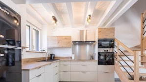 Una cocina moderna con armarios blancos, electrodomésticos de acero inoxidable y una escalera de madera.