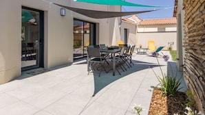 Un patio con mesa y sillas, una puerta y un pequeño jardín con plantas.