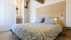 Un dormitorio con una cama grande, vigas de madera, una lámpara colgante y una mesita de noche.