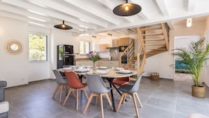 Un comedor moderno con una mesa redonda, sillas y una cocina integrada al fondo.