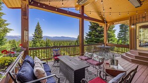 Une terrasse extérieure couverte, aménagée avec des sièges et une table, et offrant une vue sur les montagnes.