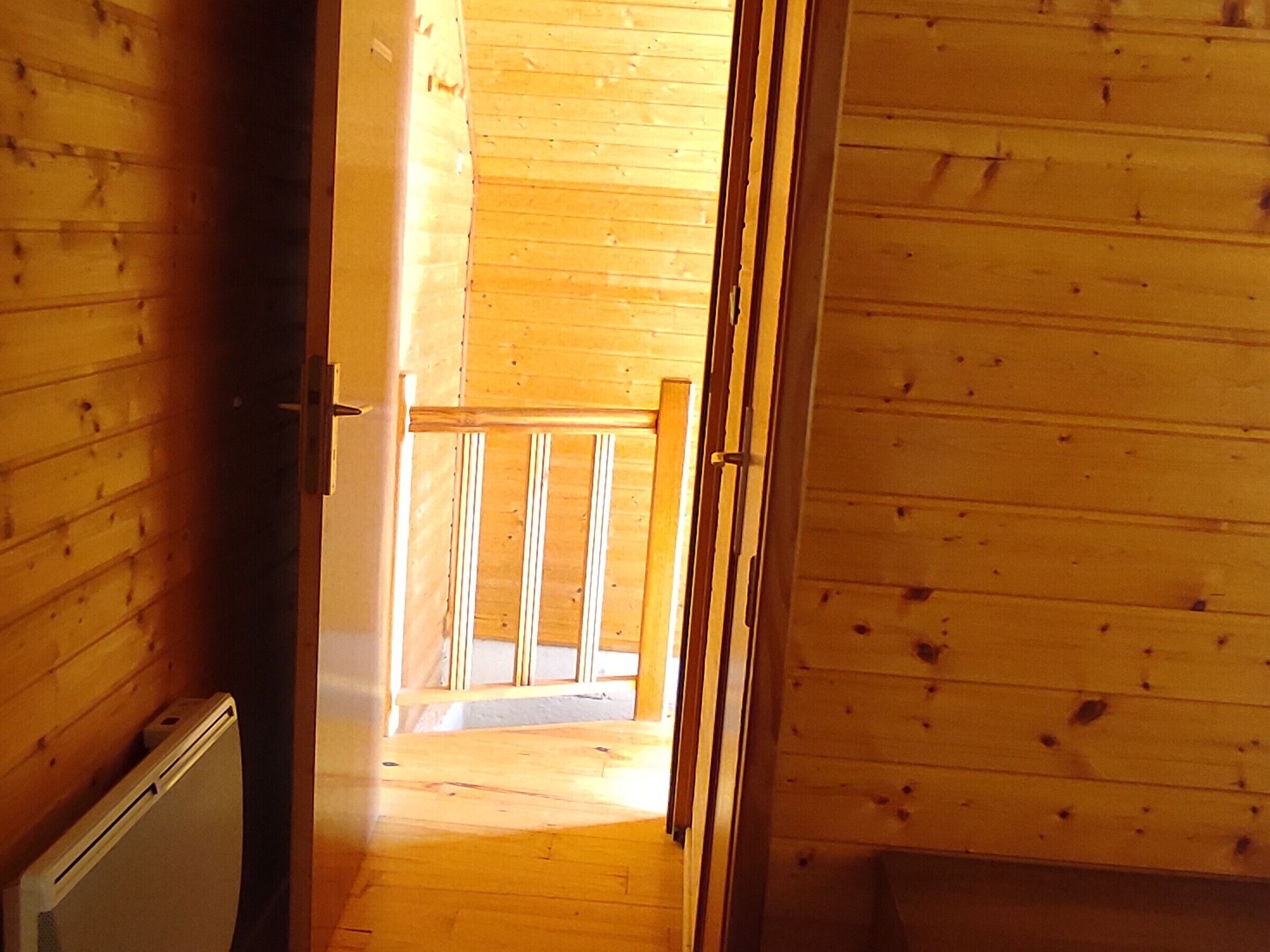 A wooden interior with a hallway leading to a balcony.