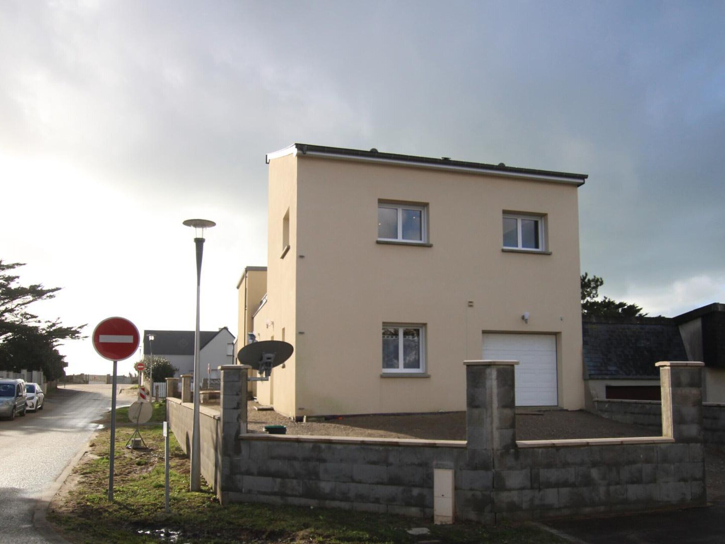 Een woongebouw met twee verdiepingen, een garage, een verboden toegang-bord en schotels.