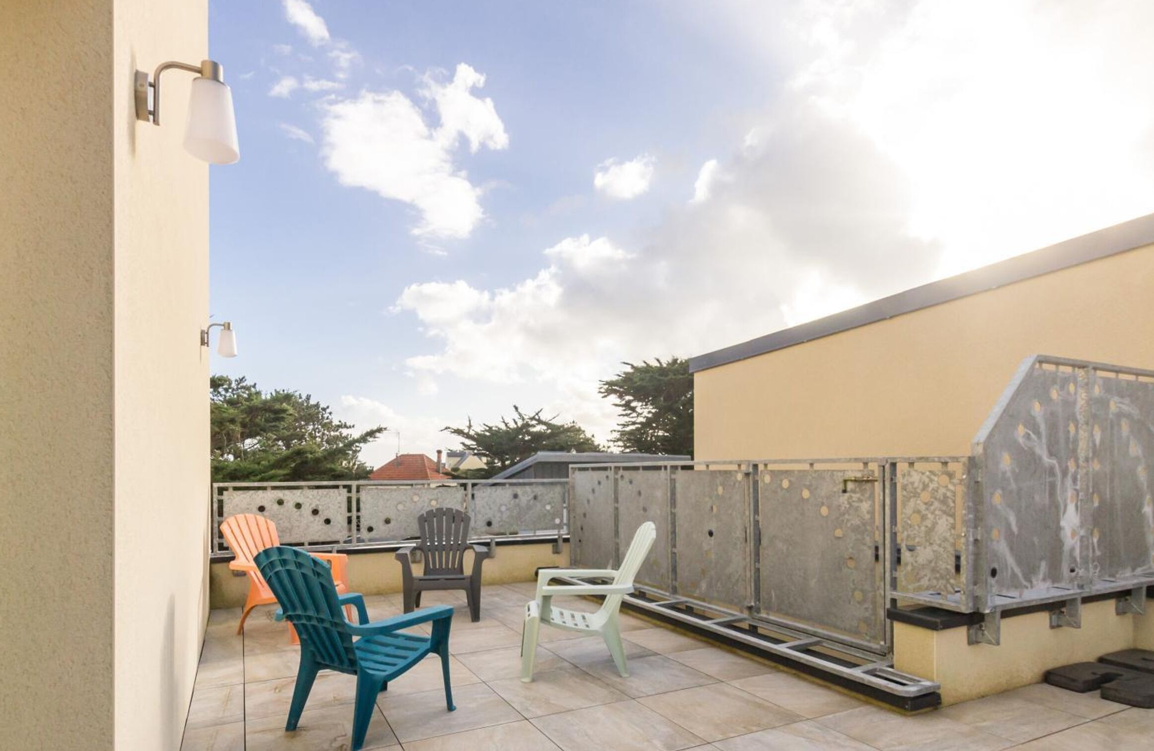 A rooftop patio with outdoor seating, a ladder, and a metal grill.