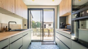 Una cocina moderna con armarios de madera, horno integrado y puerta corredera de vidrio que da a un patio exterior.