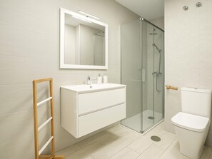 A modern bathroom with a glass shower enclosure, a white vanity with a mirror, and a toilet. - Charming Beachfront Apartment in Estepona with Wi-Fi (Estepona)