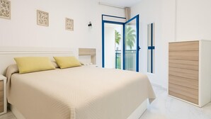 A modern bedroom with a large bed, a wardrobe, and a balcony with a view. - Charming Beachfront Apartment in Estepona with Wi-Fi (Estepona)