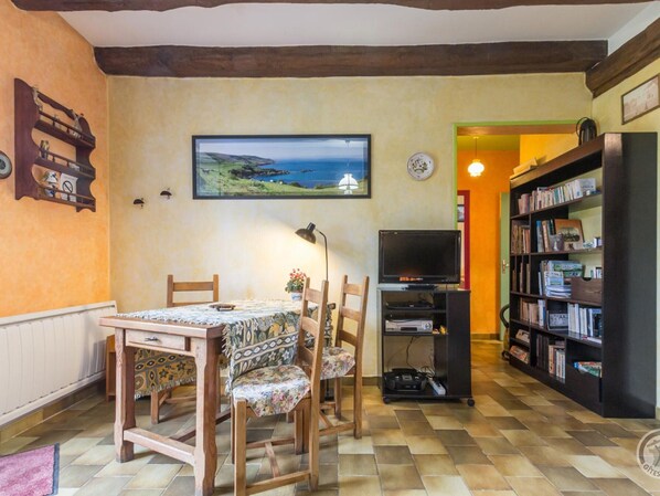 A cozy dining area with a table and chairs, a television, and a bookshelf.