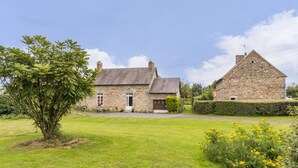 Una casa de piedra con un patio cubierto de césped y un árbol.
