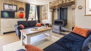 Ein gemütliches Wohnzimmer mit Kamin, Sofa, Couchtisch und Fernseher.