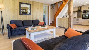 Ein modernes Wohnzimmer mit einer Couch, einem Couchtisch und einer Treppe, die in eine Küche führt.