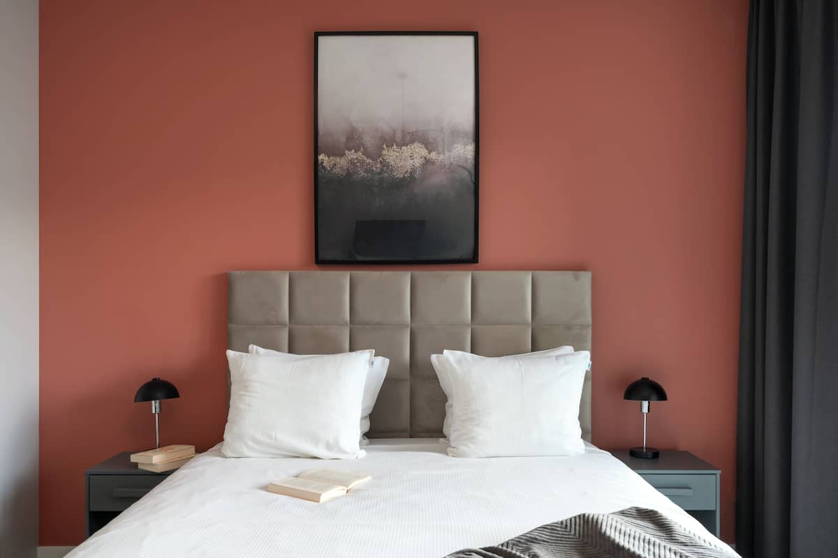 A neatly made bed with white linens, two bedside tables with lamps, and a framed picture above the bed.