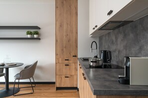 A modern kitchen with a wooden column, black countertops, and a coffee machine. - apartamenty-wroc Center by Uni Bridge (Wrocław)