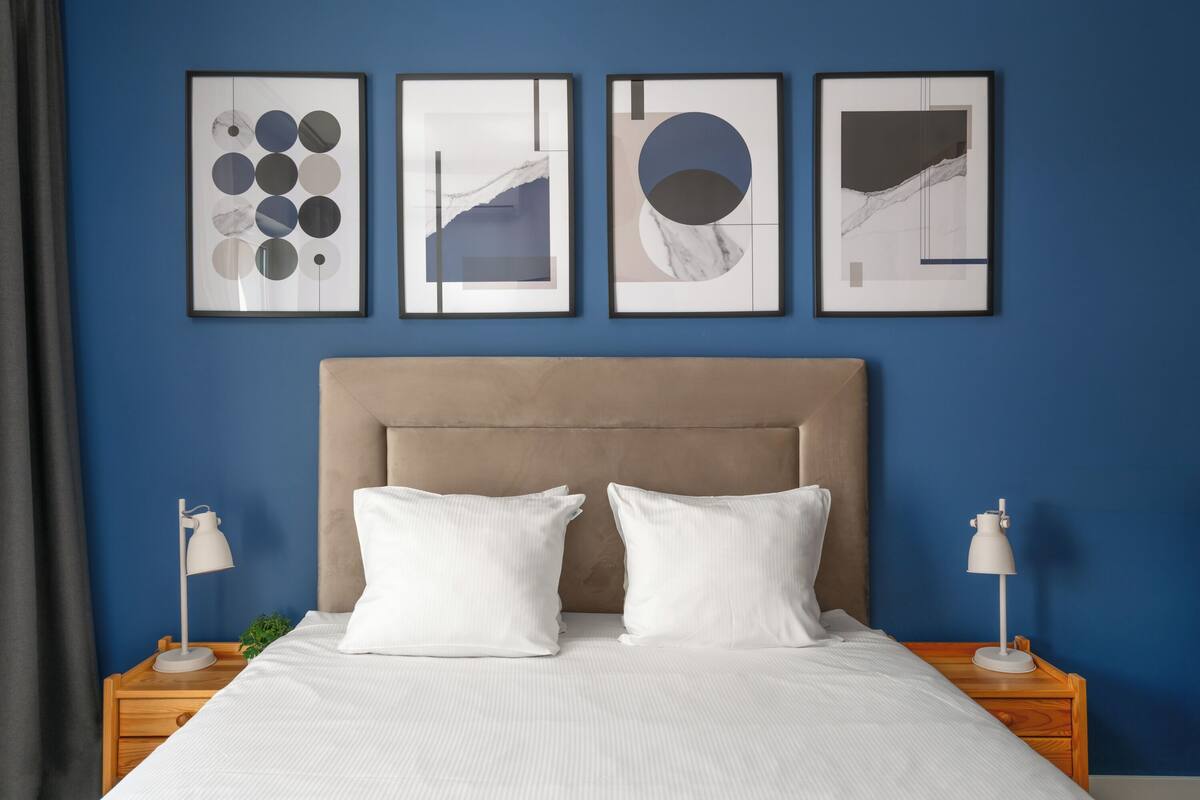 A neatly made bed with white linens, a beige headboard, and two bedside tables with lamps.