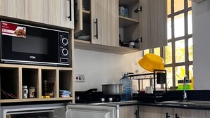 A modern kitchen with wooden cabinets, a built-in microwave, and a refrigerator stocked with food. - Jazby Guest House Naivasha (Naivasha)