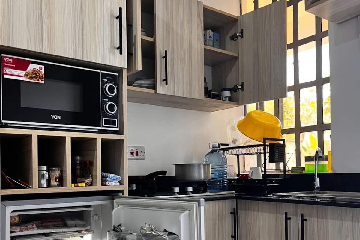 Une cuisine moderne avec des meubles en bois, un four à micro-ondes encastré et un réfrigérateur rempli de provisions.