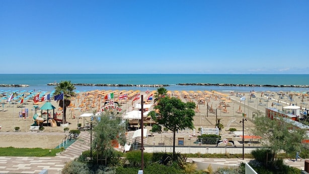 A beach with numerous umbrellas and sun loungers, a clear blue sky, and a calm sea. -  RN003 - Torre Pedrera, exclusive three-room apartment facing the sea with a balcony (Torre Pedrera)