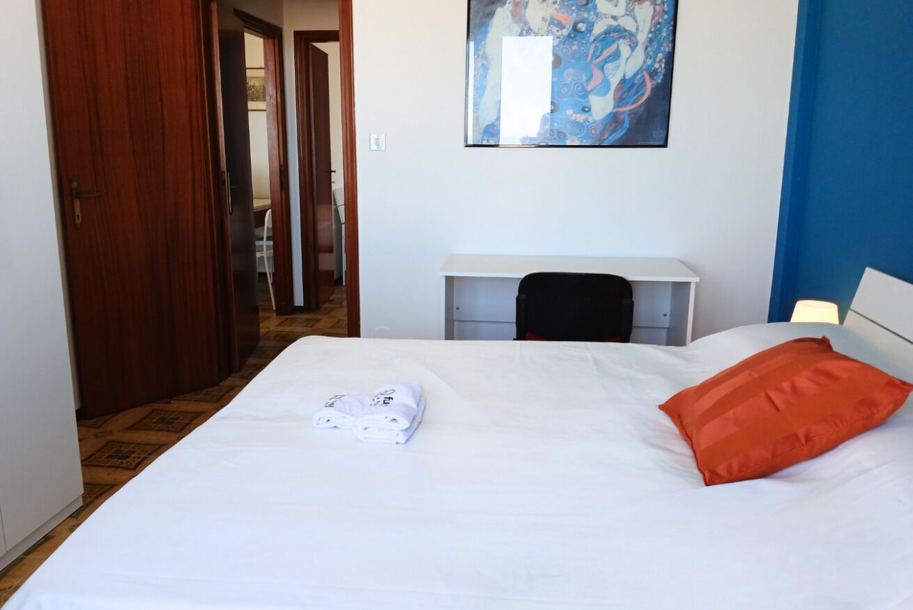 Una habitación de hotel con una cama, un escritorio, una silla y un cuadro en la pared.