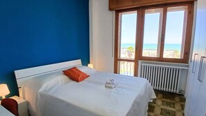 A hotel room with a bed, a window with a view of the beach, and a radiator. -  RN003 - Torre Pedrera, exclusive three-room apartment facing the sea with a balcony (Torre Pedrera)