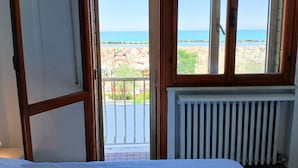 A room with a view of a beach, a radiator, and a partially open door. -  RN003 - Torre Pedrera, exclusive three-room apartment facing the sea with a balcony (Torre Pedrera)