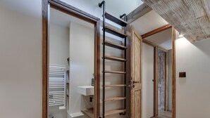 A hallway with a wooden door, a sliding shelf, and a white sink. - Val d'Isère - Flat for 7 ppl, 68 sqm (Val-d'Isère)