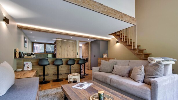A modern living room with a wooden coffee table, a sofa, and a staircase. - Val d'Isère - Flat for 7 ppl, 68 sqm (Val-d'Isère)