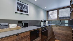 A modern kitchen with a wooden cabinet, a toaster, a coffee maker, and a framed photo on the wall. - Val d'Isère - Flat for 7 ppl, 68 sqm (Val-d'Isère)