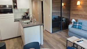 A compact living space with a kitchenette, a dining area, and a seating area with a sofa and a table.