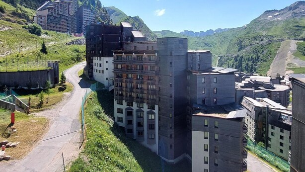 A multi-story hotel with a modern architectural design, situated in a mountainous area with lush greenery.