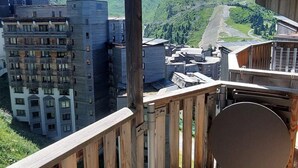A view of a mountainous area with buildings, including a multi-story hotel with balconies and a wooden deck.