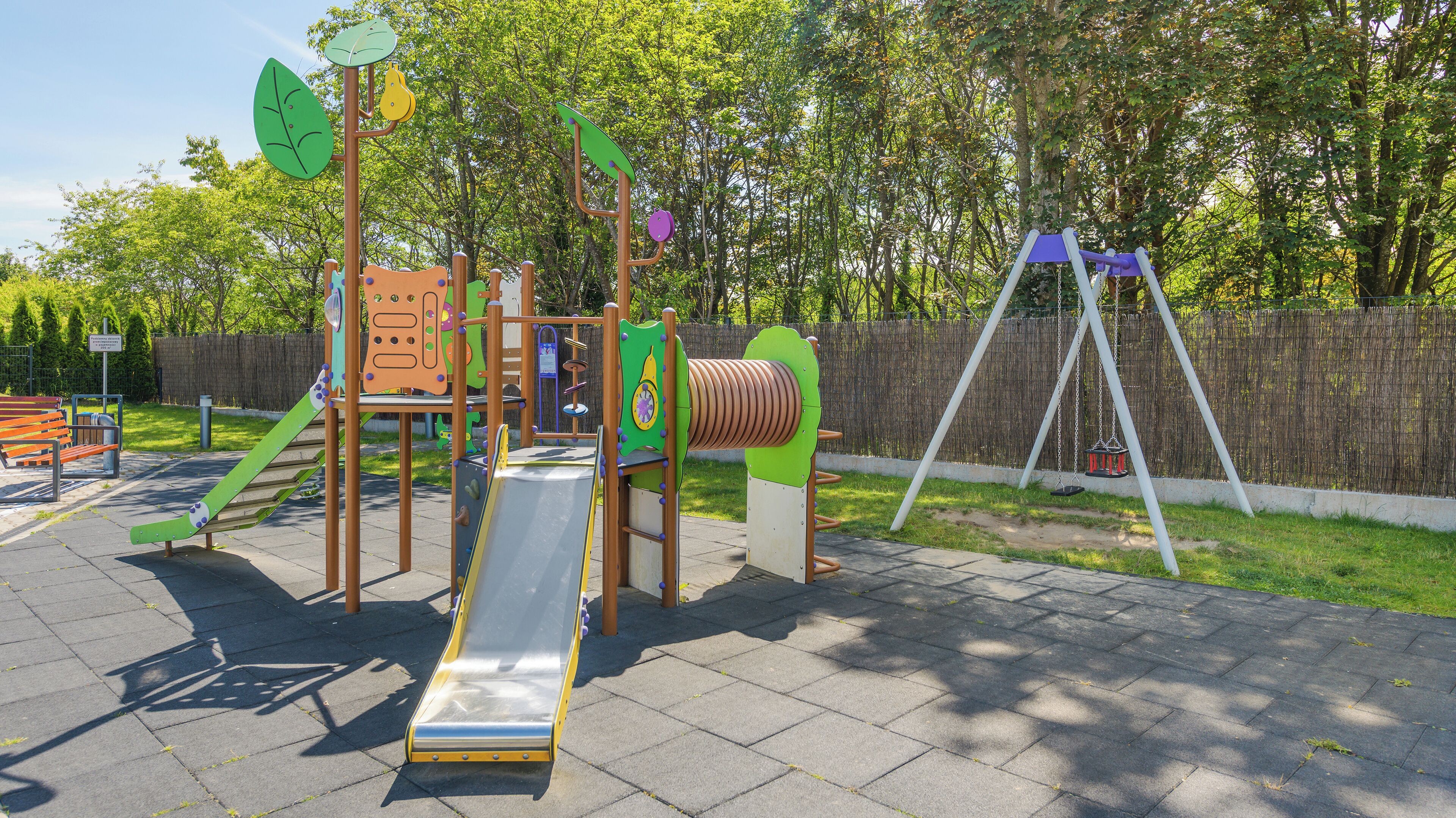 A playground with various play structures including a slide, climbing frame, and swings.
