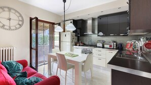 A modern kitchen with a dining area, a red sofa, and a large wall clock.
