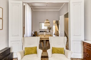 A hallway with a dining area, a staircase, and a view of the living room.