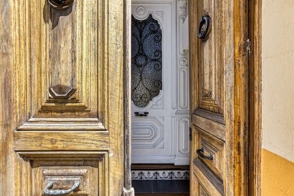 A wooden door with intricate carvings and a white door with a decorative glass panel.