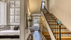 A staircase with patterned tiles, a bed with patterned bedding, and framed city maps on the wall. - Modernist Manor House for 14 – 7 Bedrooms – Central Palafrugell – Patio – Garage (Palafrugell)