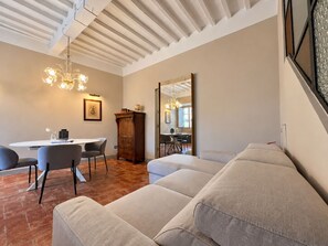 A modern living room with a sofa, dining table, chairs, and a large mirror. - Lovely apartment for 4 people with WIFI, A/C, terrace and panoramic view (Cortona)
