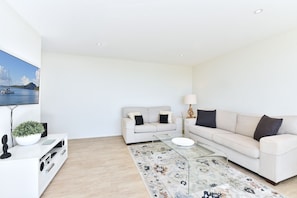 A modern living room with a sofa set, a coffee table, a TV, and a decorative rug. - Ocean Shores Waterfront Escape in Nelson Bay (Nelson Bay)