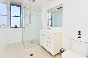 A modern bathroom with a glass-enclosed shower, a white vanity with a mirror, and a toilet.