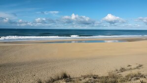 A beach with a wide sandy area and a calm sea. - Pretty Little Chalet on the Silver Coast (Le Porge)