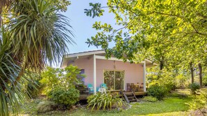 A single-story house with a porch, surrounded by lush greenery and trees. - Pretty Little Chalet on the Silver Coast (Le Porge)