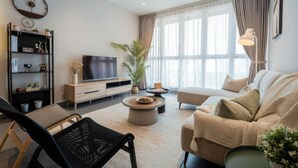 Een moderne woonkamer met een bank, salontafel, televisie, boekenkast en plafondventilator.