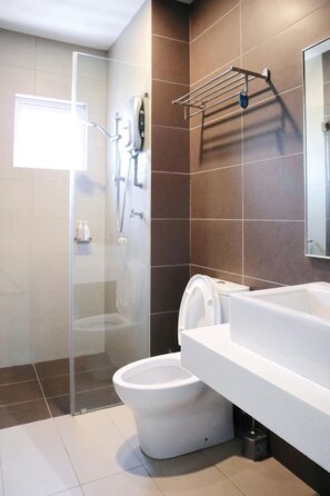 Une salle de bain moderne avec une douche à parois de verre, des toilettes blanches et un lavabo blanc avec un miroir au-dessus.